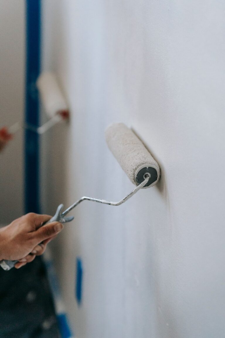 Manos pintando una pared con un rodillo (imagen de referencia de pintura y artículos para el hogar)